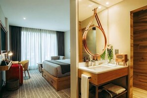 Una habitación de hotel con cama, escritorio, silla y un espejo grande.