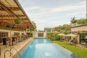 A pool area with a bar and seating, surrounded by greenery and a clear sky. - The Social House (Nairobi)
