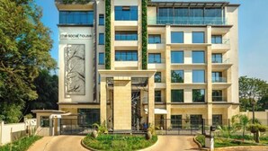 Un hôtel à plusieurs étages doté d’une entrée centrale, d’un jardin vertical et d’une enseigne indiquant « the social house ».