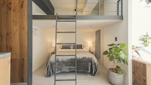 A bedroom with a bunk bed, a ladder, a bedside table with a lamp, and a potted plant. - illi Sun Shimokitazawa (Tokyo)