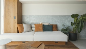 A modern living room with a white sofa, wooden accents, and a large potted plant. - illi Sun Shimokitazawa (Tokyo)