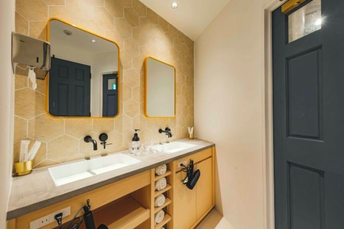 A modern bathroom with two sinks, a mirror, and a towel rack.