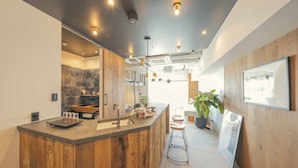 A modern kitchen with a wooden island, built-in appliances, and a large window providing natural light. - illi Sun Shimokitazawa (Tokyo)