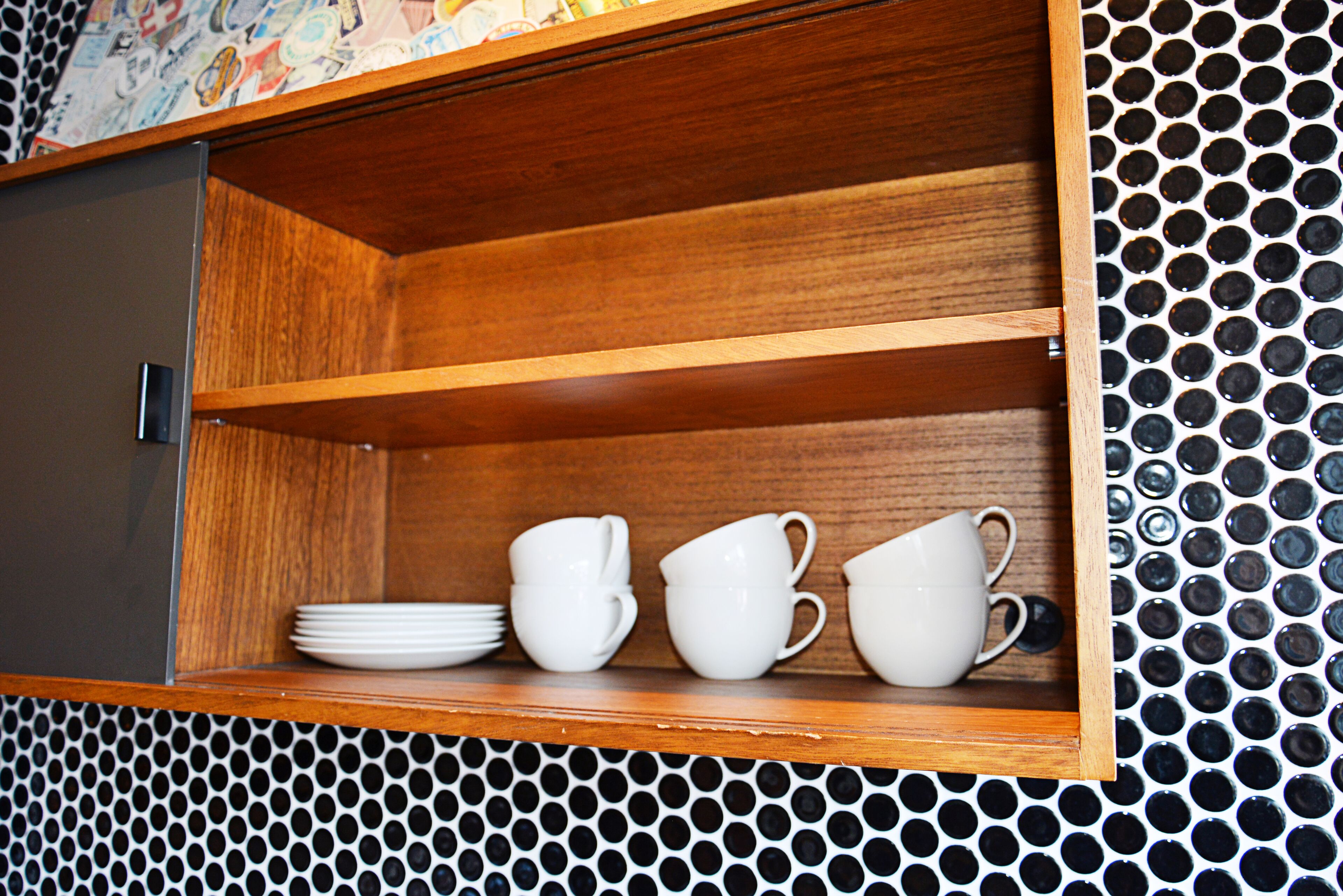 A wooden cabinet with white dishes and cups.