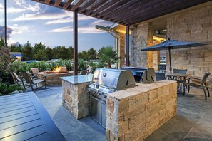 An outdoor patio with a stone barbecue and seating area.