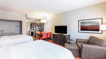 A hotel room with two beds, a dining area, a TV, and a painting on the wall.