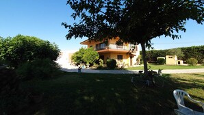 A two-story house with a balcony, surrounded by greenery and a clear sky. - Mas Turró - Castelló d'Empúries (Castellón de Ampurias)