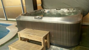 A hot tub with a control panel, a wooden stool, and a pool. - Mas Turró - Castelló d'Empúries (Castellón de Ampurias)