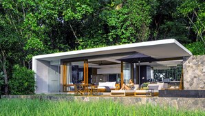 A modern house with a glass facade, outdoor seating area, and lush greenery. - Haritha Villas & Spa (Hikkaduwa)