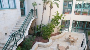 A courtyard with a staircase, outdoor seating area, and potted plants. - HI Pkiin Hostel (Peki'in)