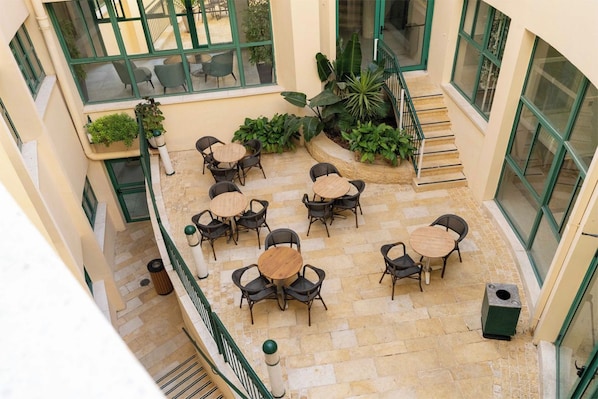 A multi-level outdoor patio with multiple seating areas, surrounded by large windows and potted plants.