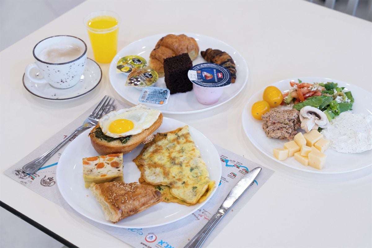 A table with breakfast items including eggs, pastries, and a fruit salad.
