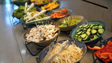 A buffet with various food options including mushrooms, cucumbers, and shredded cheese.