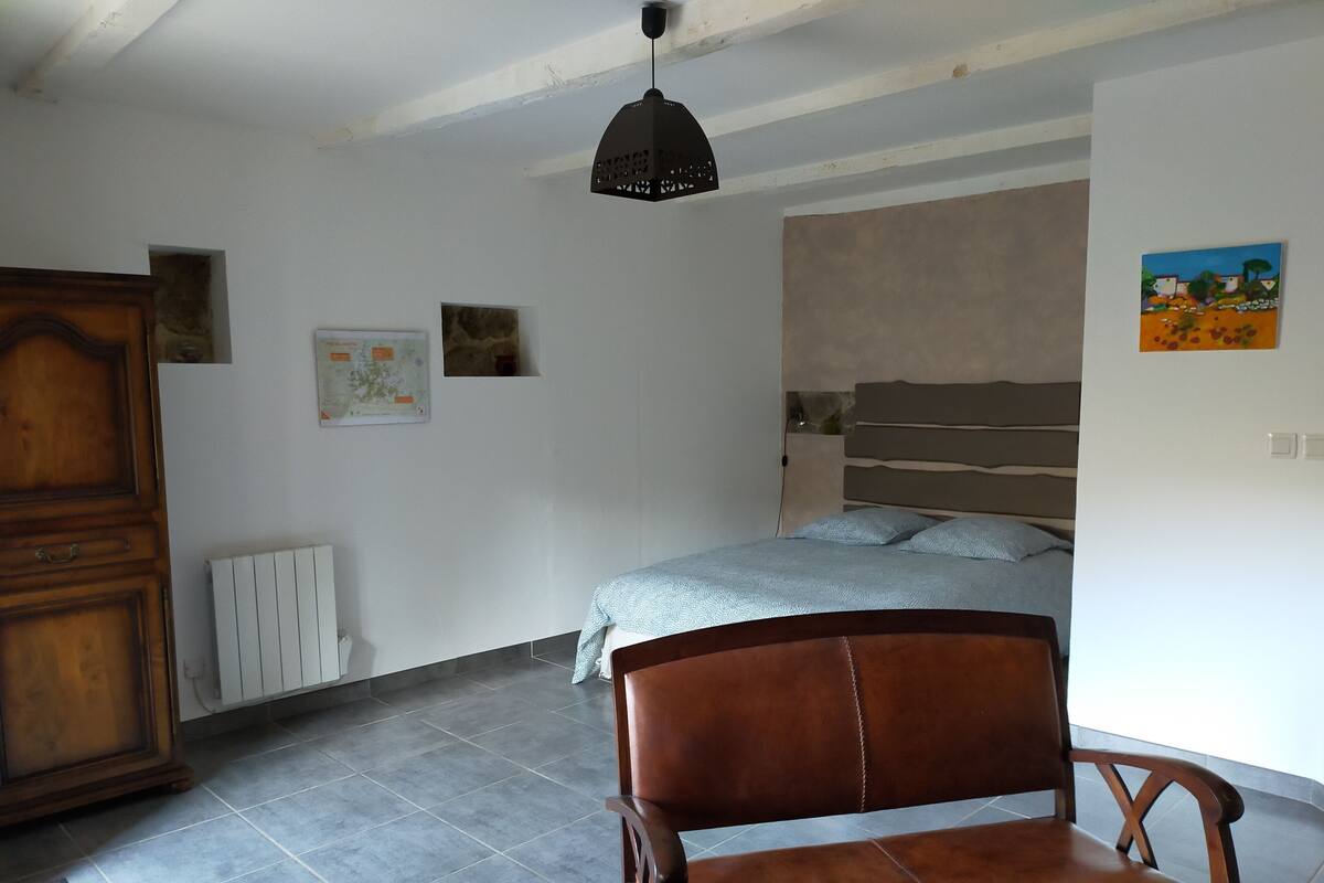 Ein Schlafzimmer mit einem Bett, einem Holzstuhl, einer Karte an der Wand und einer Heizung.