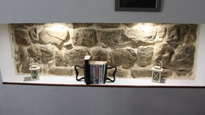 A stone wall shelf with books and lanterns. - Le Bouchon de Campagne (Saint-Barthelemy-Grozon)