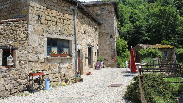 A stone building with a rustic exterior, a wooden fence, and a gravel path leading to a wooden door. - Le Bouchon de Campagne (Saint-Barthelemy-Grozon)