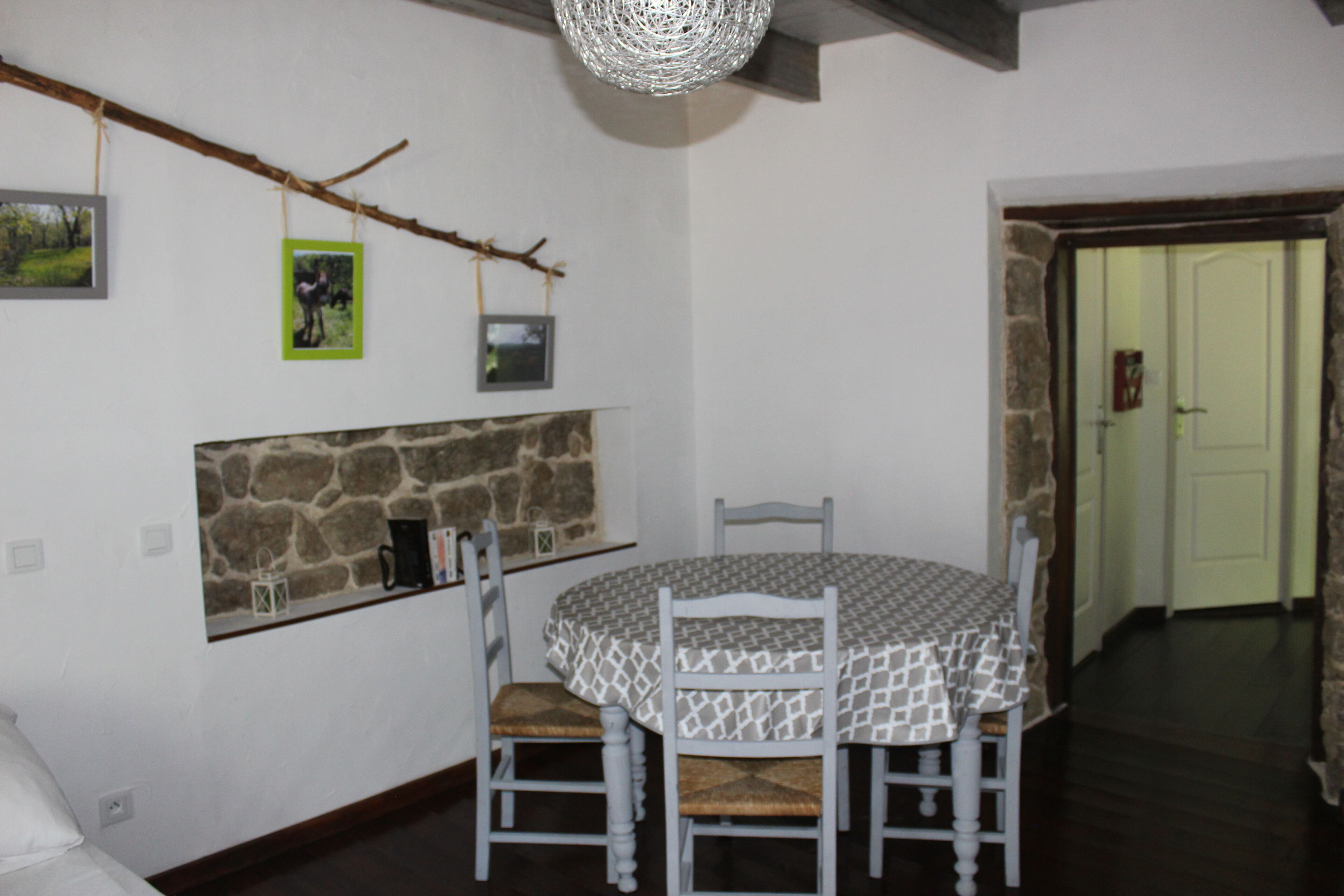 A dining area with a round table, four chairs, and a stone wall.