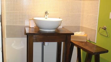 Een badkamer met een wit wastafel, houten wastafelmeubel en een spiegel erboven.