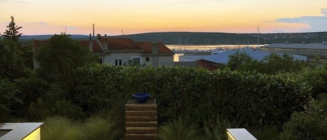 A modern outdoor patio area with a view of a marina and distant hills.