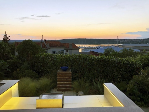 A modern outdoor patio area with a view of a marina and distant hills.