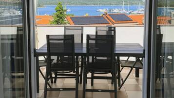 A balcony with a checkered floor, two chairs, and a table.