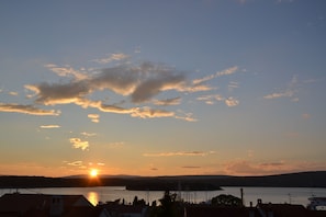 A sunset over a body of water with boats and buildings in the foreground.