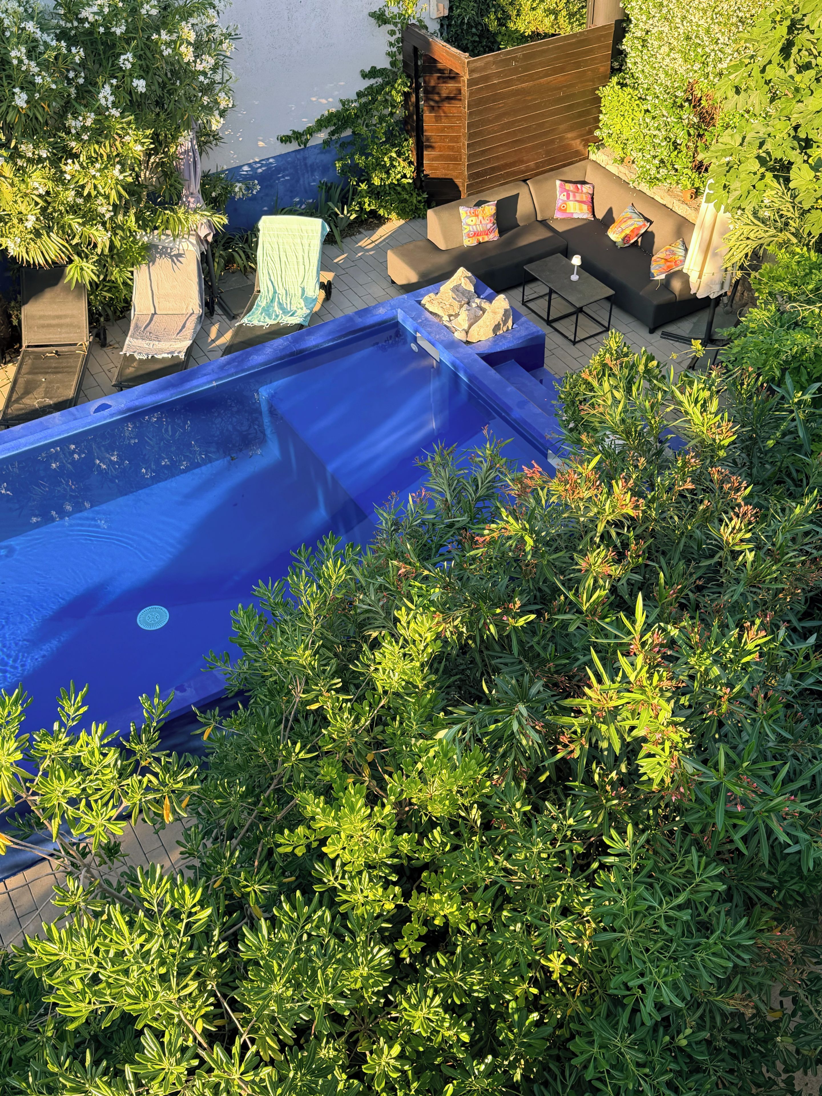Una piscina con un deck circundante, que incluye asientos tipo lounge y una valla de madera.