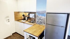 Uma cozinha compacta com armários brancos, bancada de madeira e geladeira de aço inoxidável.
