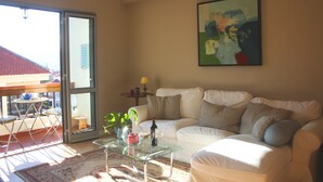 A living room with a glass coffee table, white sofa, and a painting on the wall. - Peaceful Top Floor Apt W Balconies-Cambridge RIGHT (AC) (Funchal)