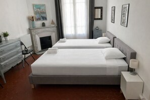 Une chambre d’hôtel avec deux lits, une cheminée, une commode et une table de chevet avec une lampe.