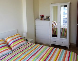 Une chambre à coucher avec un lit, une commode blanche et un miroir.