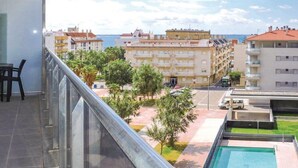Un balcón con vistas a una zona residencial, una piscina y una calle con coches aparcados.
