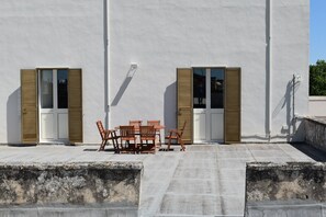 A rooftop terrace with a table and chairs, two doors with shutters, and a concrete floor. - Calle Dei Saraceni (Carmiano)