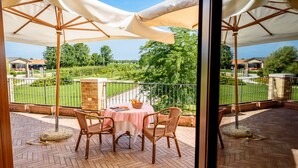 Un patio con tavolo e sedie, vista su un giardino e una recinzione.