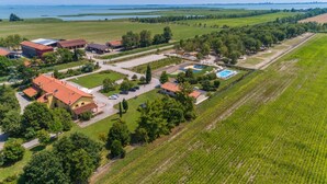 Una vista aerea di una zona residenziale con case, una piscina e campi verdi circostanti.