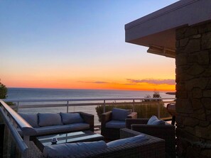 A balcony with wicker furniture and a view of the ocean at sunset. - Large family villa with an exceptional view of the Calanques—sleeps 10 (Ensuès-la-Redonne)