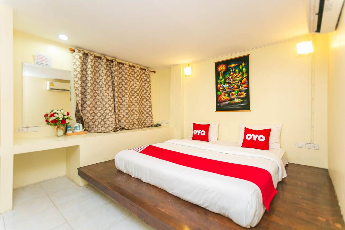 A hotel room with a bed, a desk, and a window with curtains.