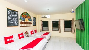 Une chambre d’hôtel avec deux lits, une télévision et des œuvres d’art accrochées aux murs.
