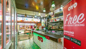 L’intérieur d’un restaurant avec un comptoir, des luminaires suspendus et une enseigne publicitaire annonçant une application gratuite.