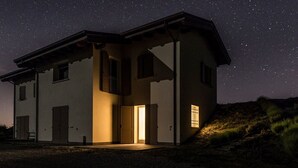 Una casa a due piani con tetto spiovente, un ingresso centrale e un piccolo portico.