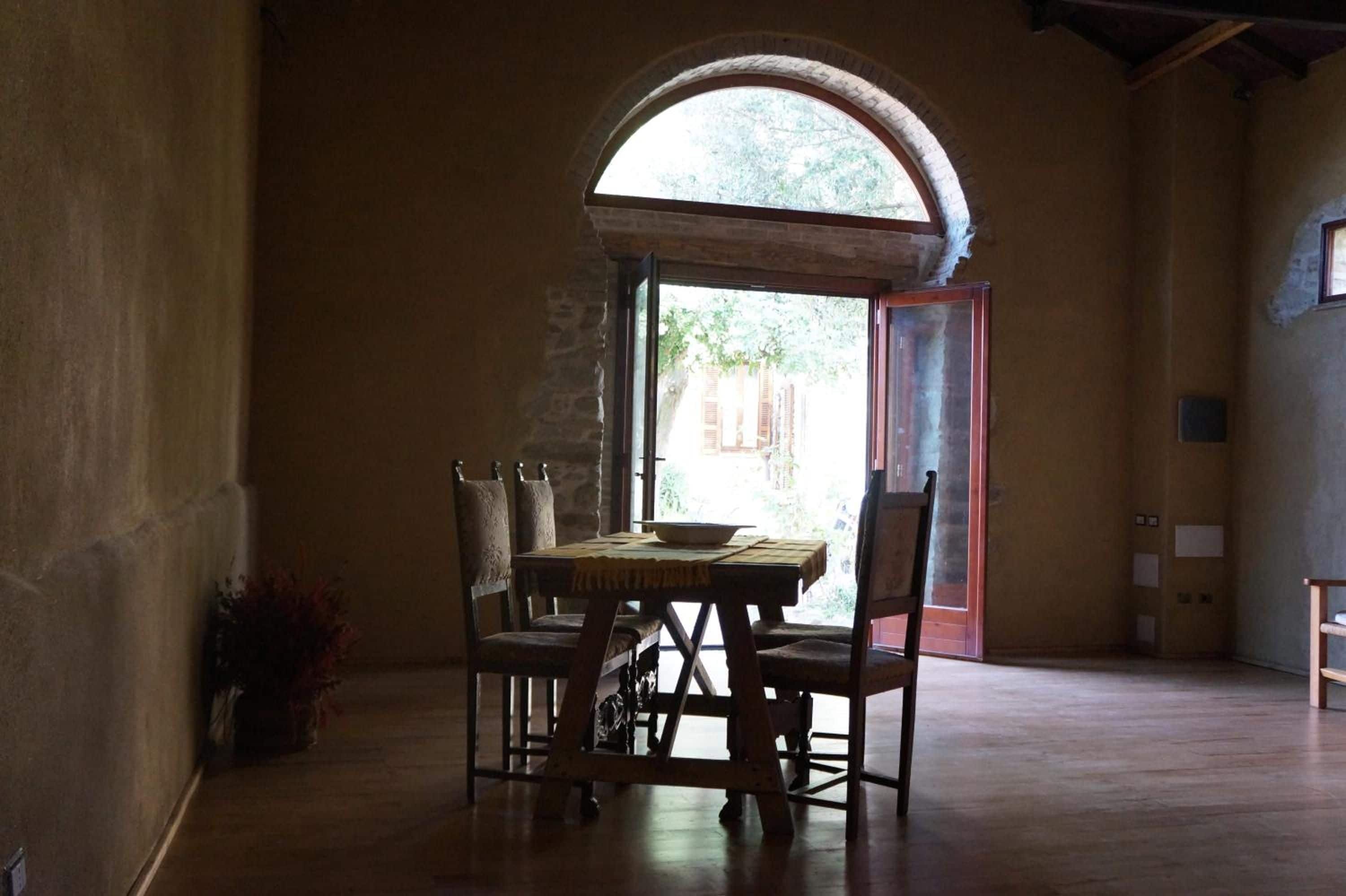 Un comedor con una mesa y sillas, un amplio ventanal de arco y vistas al exterior.