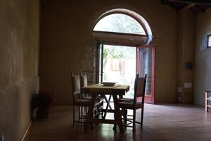 Un comedor con una mesa y sillas, un amplio ventanal de arco y vistas al exterior.