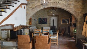 A rustic interior with a stone fireplace, wooden furniture, and a staircase. - Sa Domu De Sa Contissa (Selegas)