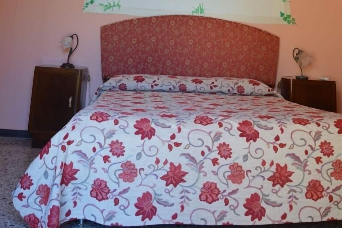 Ein Schlafzimmer mit einem Bett, einem Kopfteil, Wandmalerei und zwei Nachttischen.