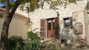 A stone building with wooden shutters, a small window, and potted plants. - Sa Domu De Sa Contissa (Selegas)