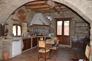Una cocina rústica con paredes de piedra, muebles de madera y salpicadero de azulejos.