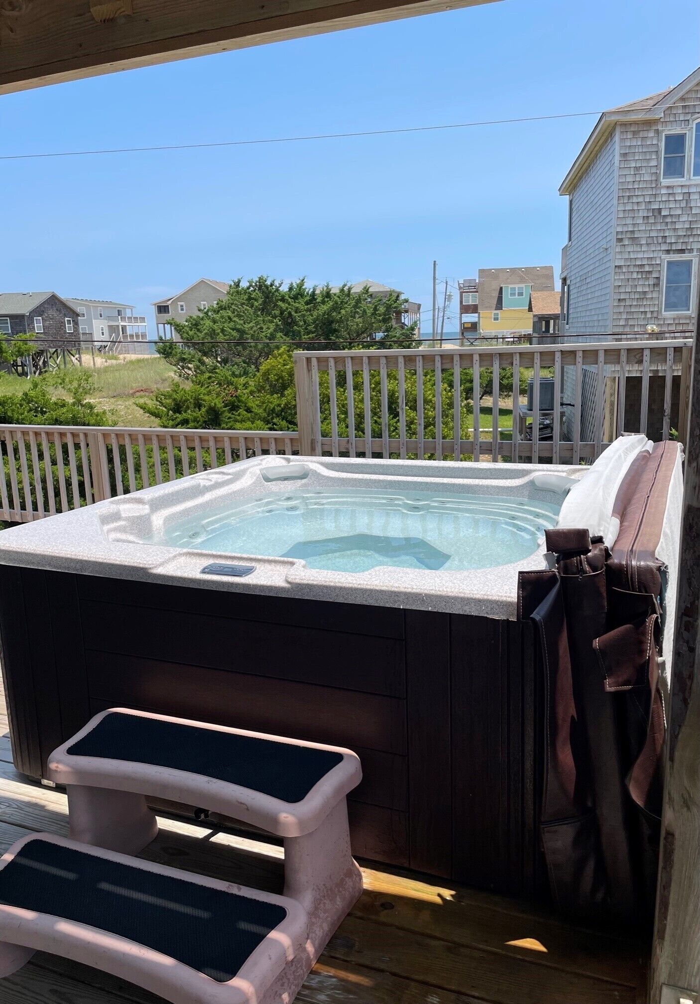 Een hottub op een houten terras, met uitzicht op huizen.