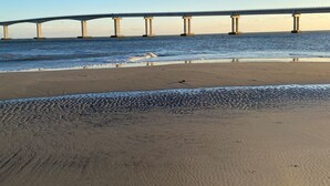 Une plage avec un pont en arrière-plan.