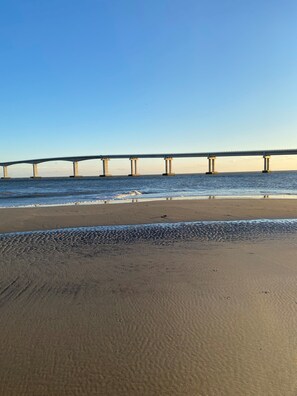 A beach with a bridge in the background.