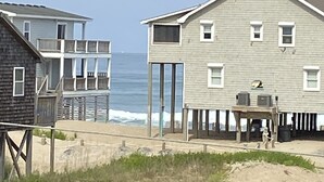 Une propriété située en bord de mer, comprenant une grande maison dotée d’un balcon et un bâtiment plus petit attenant.